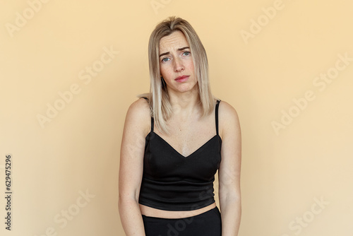 Εκτύπωση καμβά Sad and indifferent young woman with freckles, looking with boredom at camera, s
