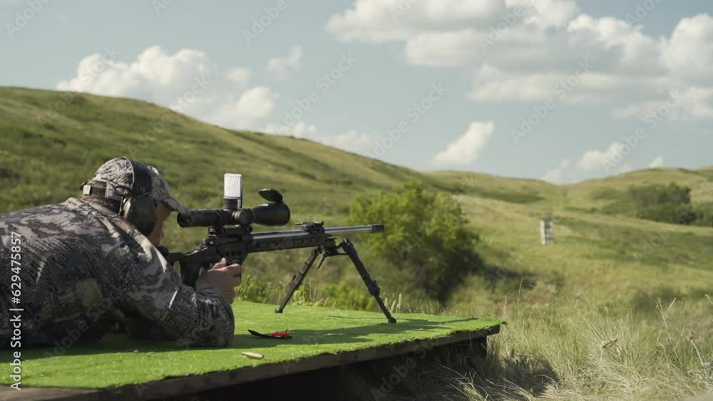 A shooter in camouflage uniform shoots at a target with a sniper rifle A shooter in camouflage uniform shoots at a target with a sniper rifle