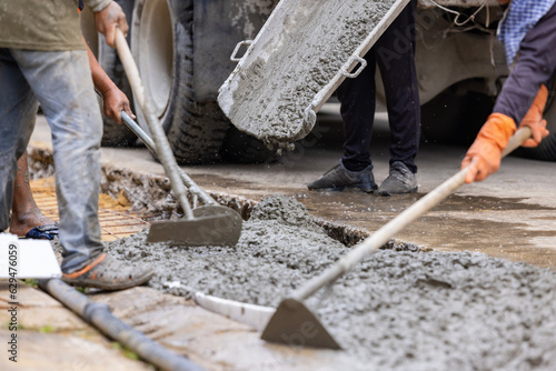 Workers pour the Foundation for the construction of paving a driveway using mobile concrete mixers or concrete mixer truck. Spreading concrete for sidewalk repair