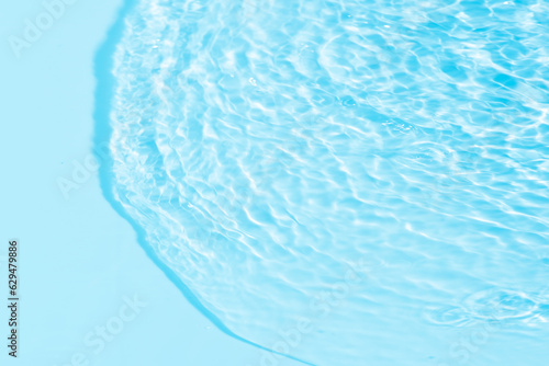 Blue water with ripples on the surface. Defocus blurred transparent blue colored clear calm water surface texture with splashes and bubbles. Water waves with shining pattern texture background.