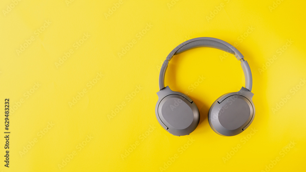 Gray wireless headphones on yellow background , Online learning design concept. Top view of ,Top view with copy space for text Gray wireless headphones on yellow background , Online learning design concept. Top view of ,Top view with copy space for text