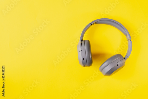 Gray wireless headphones on yellow background , Online learning design concept. Top view of ,Top view with copy space for text