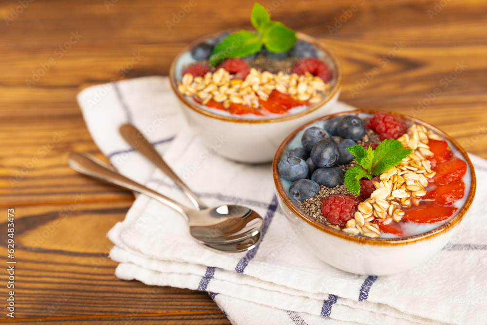 Bowl of granola with yogurt and fresh berries on a texture table. Yogurt berries, acai bowl, spirulina bowl. Healthy food, balanced breakfast. Strawberries, blueberries, kiwi, peach, almonds and chia. Bowl of granola with yogurt and fresh berries on a texture table. Yogurt berries, acai bowl, spirulina bowl. Healthy food, balanced breakfast. Strawberries, blueberries, kiwi, peach, almonds and chia.