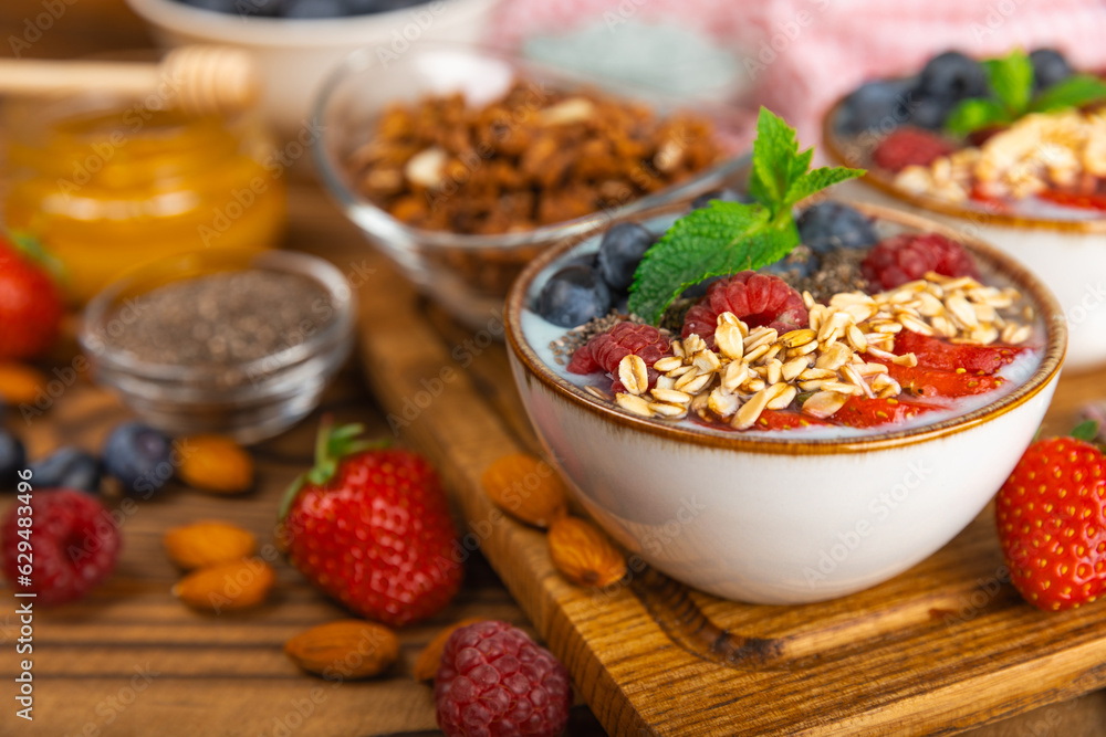 Bowl of granola with yogurt and fresh berries on a texture table. Yogurt berries, acai bowl, spirulina bowl. Healthy food, balanced breakfast. Strawberries, blueberries, kiwi, peach, almonds and chia. Bowl of granola with yogurt and fresh berries on a texture table. Yogurt berries, acai bowl, spirulina bowl. Healthy food, balanced breakfast. Strawberries, blueberries, kiwi, peach, almonds and chia.
