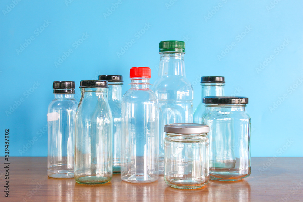 empty used glass bottle on wood desk with blue background. Recycle glass bottles and safe the earth concept. 