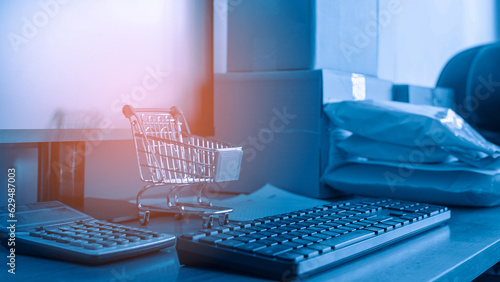 Close up of computer keyboard with small shopping cart, calculator and Pakaging box. Ecommerce and Online shopping Concept.  photo