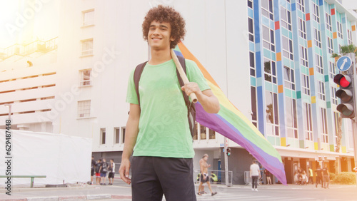 Smiling handsome young man with LGBT flag in his hands