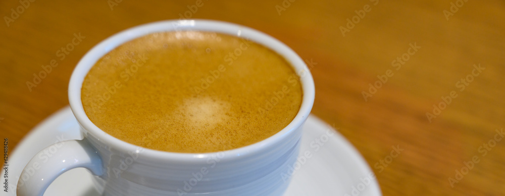 Hot Coffee in white cup on wooden table in kitchen room at comfort home. Banner cover size.