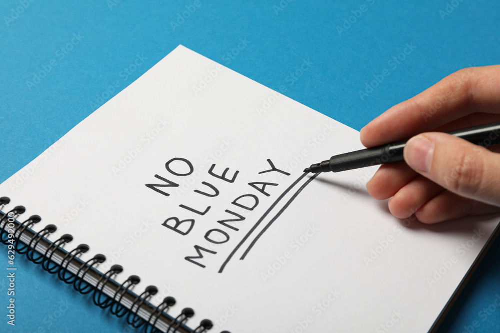Notepad with text No Blue Monday, marker in hand on blue background Notepad with text No Blue Monday, marker in hand on blue background