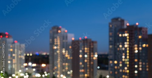 Unfocused background: evening city lights of high-rise buildings. Evening city lights banner © ilyaska