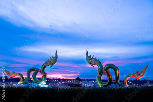 Big green naga statue in riverside on mekong river is landmark in nongkhai city Thailand with twilight background. photo