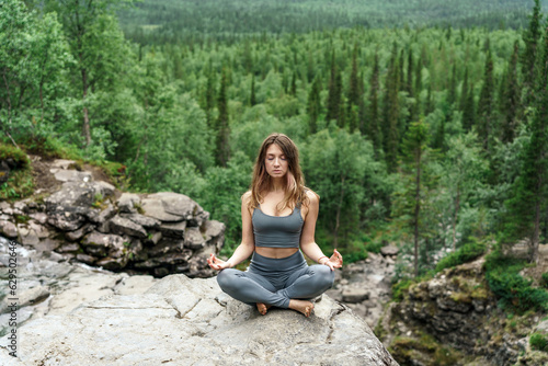 Meditation balance and harmony  a female trainer does yoga exercise lotus pose against the backdrop of the nature of the north.