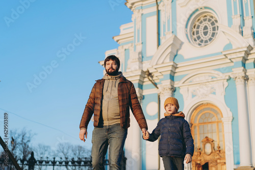 Young father walking with little son from orthodox cathedral holding child by hand photo