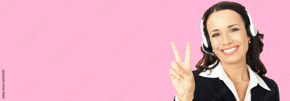 Call center service. Customer support phone sales operator in headset showing two fingers or victory gesture, over rose pink background with copy space area for text or slogan. Call center service. Customer support phone sales operator in headset showing two fingers or victory gesture, over rose pink background with copy space area for text or slogan.