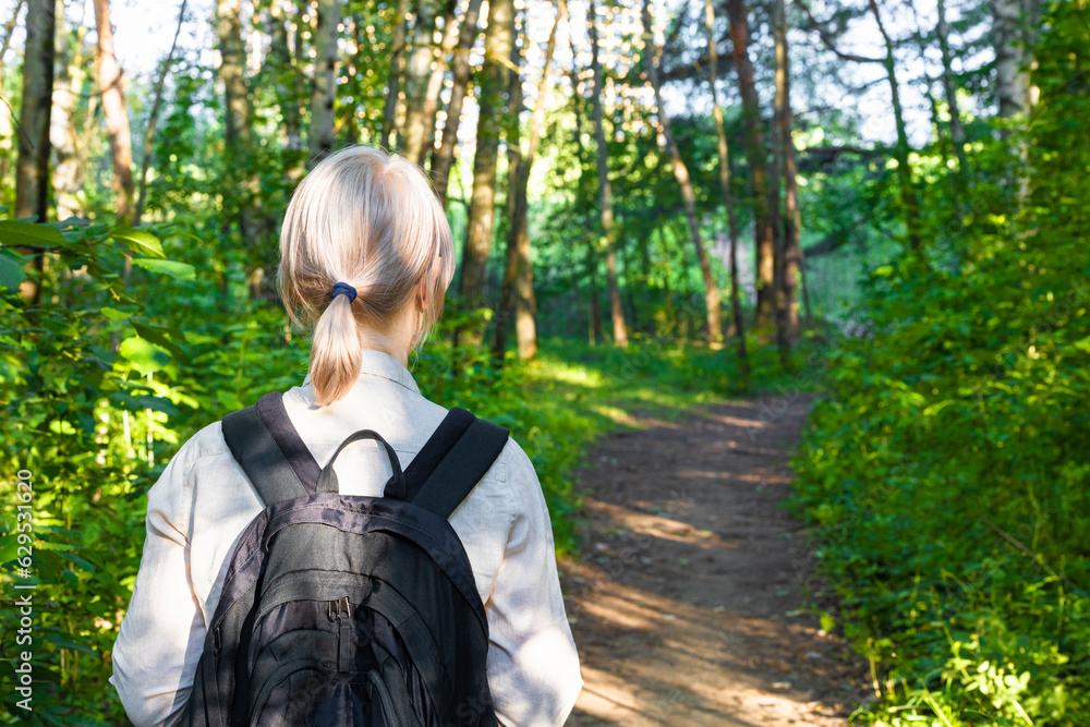 Moscow, Russia - July 03, 2023: a girl with a backpack walks through the woods. Moscow, Russia - July 03, 2023: a girl with a backpack walks through the woods.