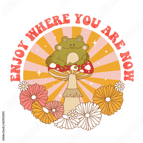 Retro 70s groovy funky frog with mushroom, flowers and sunburst. Enjoy where you are now slogan print with frog character sitting on mushroom. Naive groovy psychedelic vintage illustration.