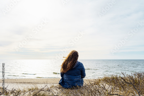 Obraz na plátně Long-haired curly plus size woman on the seashore, rear view