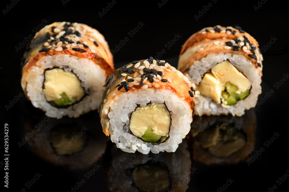 Close-up of sushi rolls with tuna, cucumber and avocado on a black background. Close-up of sushi rolls with tuna, cucumber and avocado on a black background.