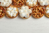 Many different tartlets on white wooden table, top view and space for text. Delicious dessert