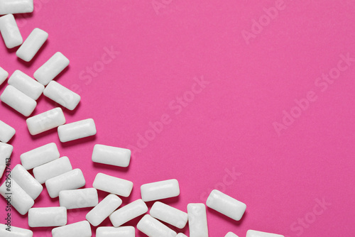 Tasty white chewing gums on pink background, flat lay