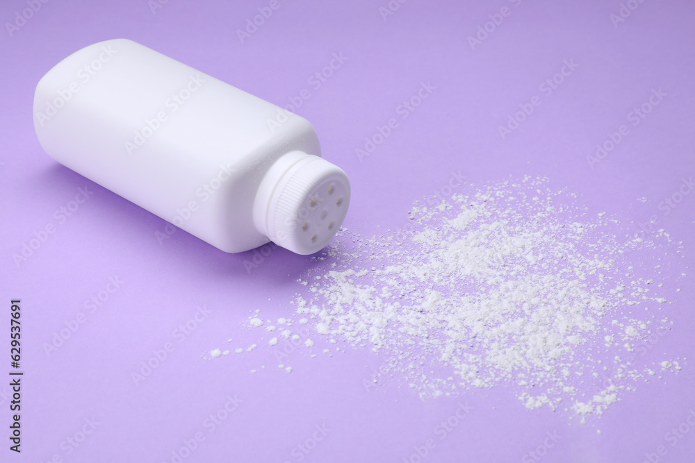 Bottle and scattered dusting powder on violet background. Baby cosmetic product Bottle and scattered dusting powder on violet background. Baby cosmetic product