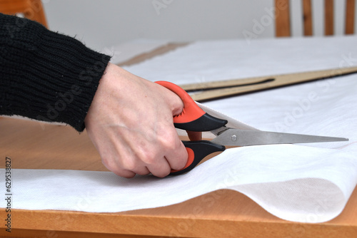 woman cutting a white cloth with scissors