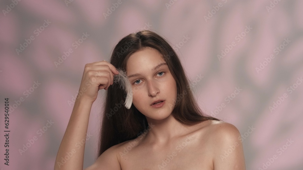 Beautiful young brunette model with long hair holding a small feather Beautiful young brunette model with long hair holding a small feather
