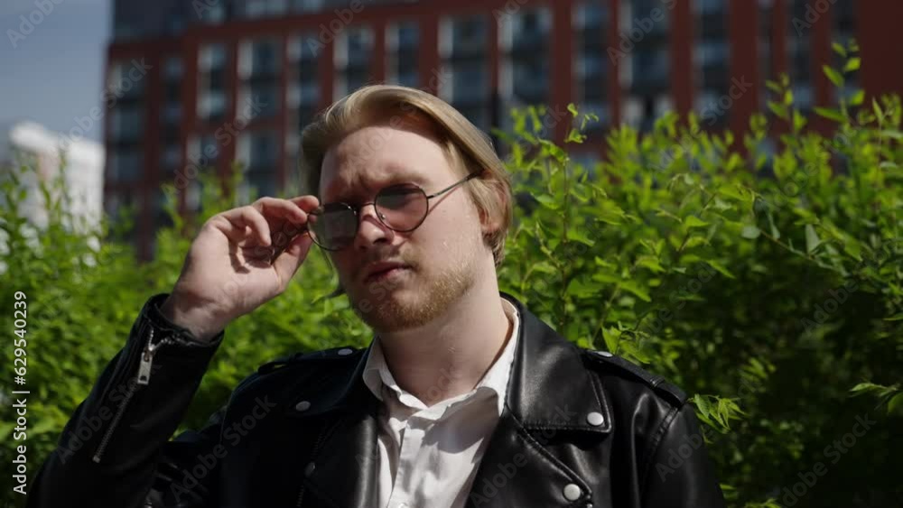 A man wears sunglasses against a background of green vegetation. Brutal look in a young guy. A man wears sunglasses against a background of green vegetation. Brutal look in a young guy.
