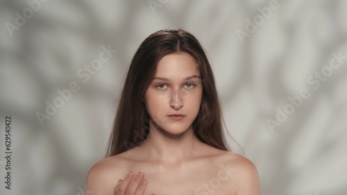Appealing female model touching her body pure skin, looking at the camera