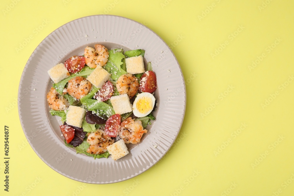 Delicious Caesar salad with shrimps on yellow background, top view. Space for text Delicious Caesar salad with shrimps on yellow background, top view. Space for text