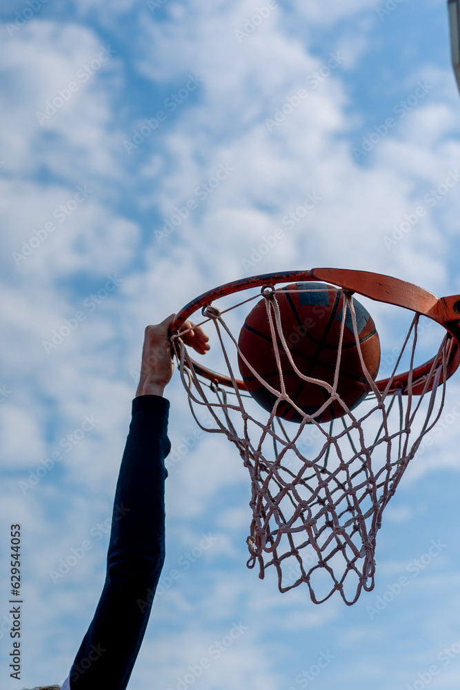 Close-up of a basketball hoop where a tall guy basketball player is scoring a dunk The concept of admiration for the game of basketball