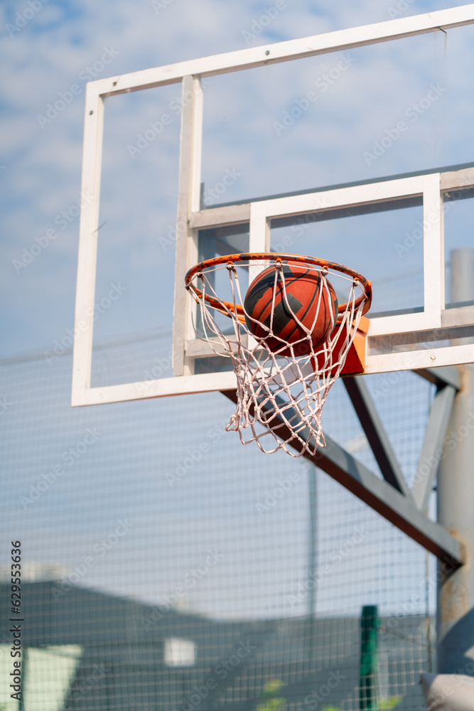 A close-up of a basketball hoop into which a basketball hits the concept of admiration for the game of basketball and love of working out 