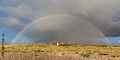 Himmel mit Regenwolken und Regenbogen über dem Strand der Ostsee auf Fehmarn in Schleswig-Holstein. Unter dem Regenbogen der Leuchtturm Westermarkelsdorf photo