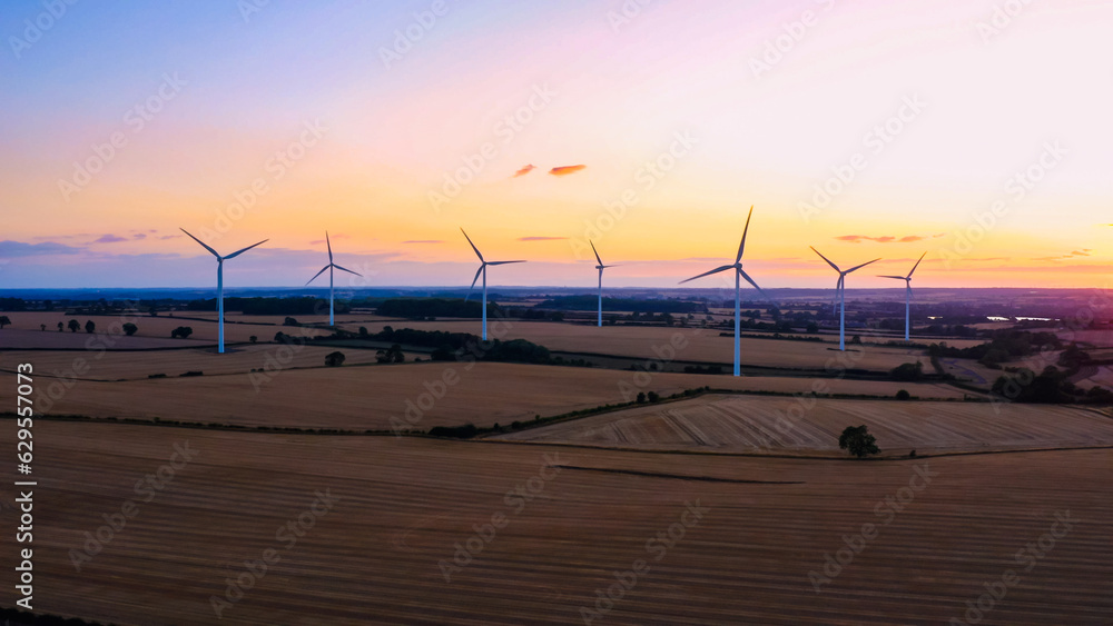 Wind turbines at sunset in rural UK landscape with golden fields
