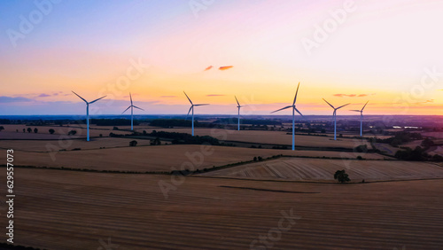 Obraz na płótnie Wind turbines at sunset in rural UK landscape with golden fields w salonie