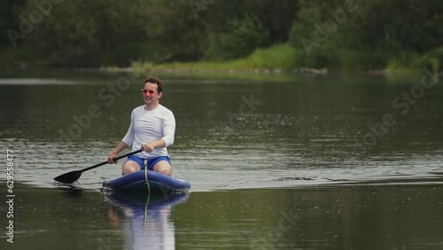 man on the soup board. a man rows with an oar on a board. a man swims across a pond alone. High quality Full HD video recording photo