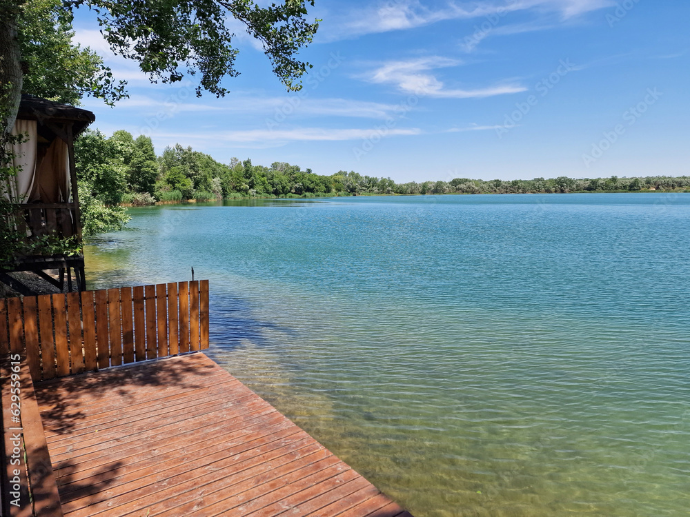 Transparent blue lake on a sunny summer day with a wooden path on the shore