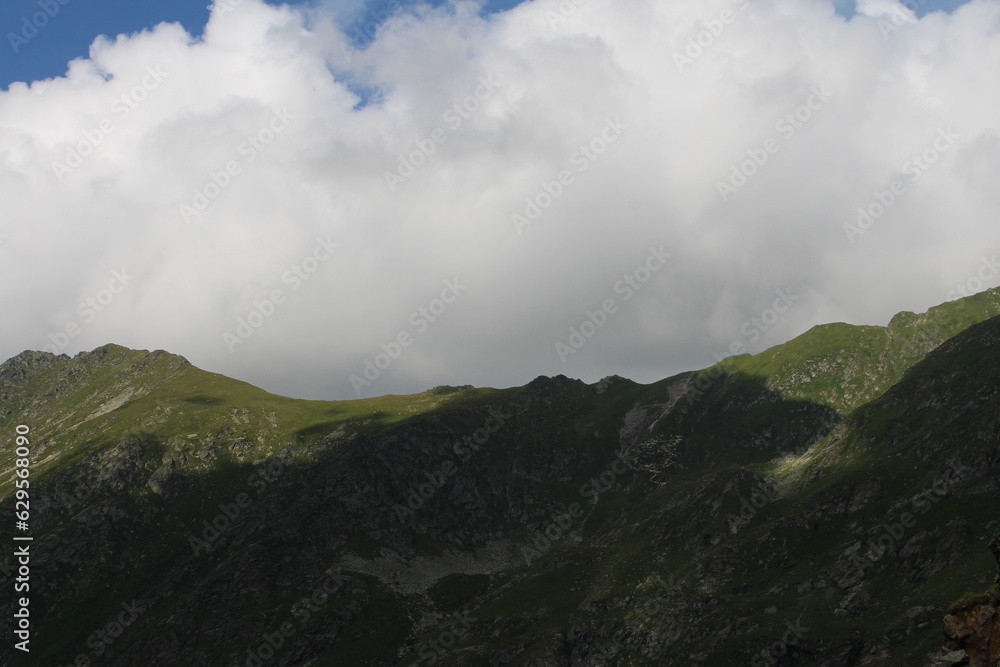 A mountain with green grass and clouds A mountain with green grass and clouds