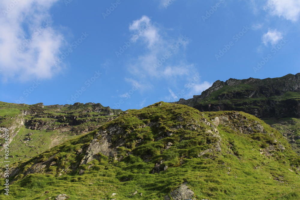A green mountain with blue sky and clouds