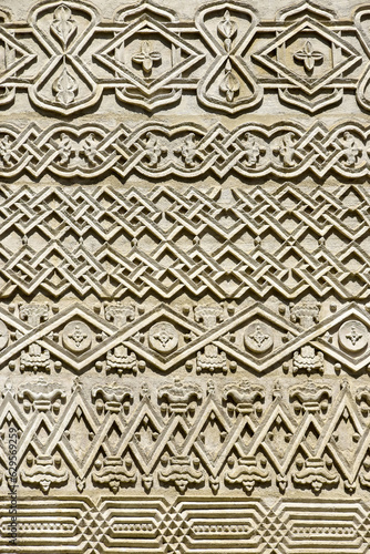 Carved embossed patterns on the stone wall of an ancient church building as a background. Fragment, detail. Architectural features. Close-up. Selective focus.