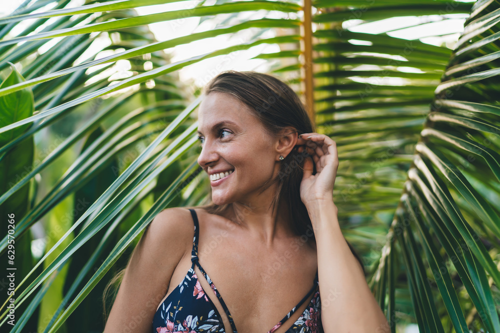 Positive woman in bikini near palm leaves Positive woman in bikini near palm leaves
