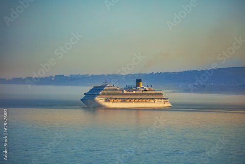 Huge cruise ship at sunset with Spanish coast on background photo