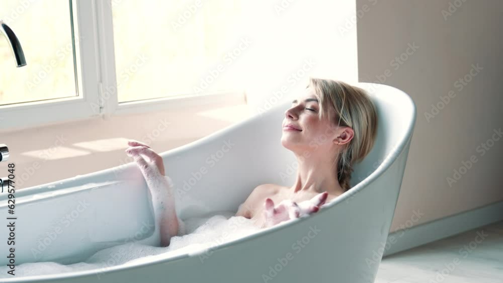 Portrait of young beautiful sexy woman having fun while lying in bathtub full of foam at home. Charming smiling model relaxing in luxury bath interior. Female enjoying beauty and skincare day Portrait of young beautiful sexy woman having fun while lying in bathtub full of foam at home. Charming smiling model relaxing in luxury bath interior. Female enjoying beauty and skincare day