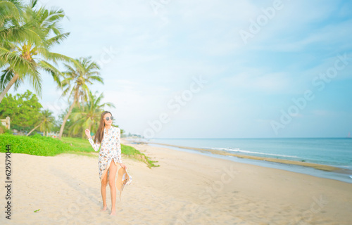 Asian woman wearing sunglasses is relaxing on the beach.