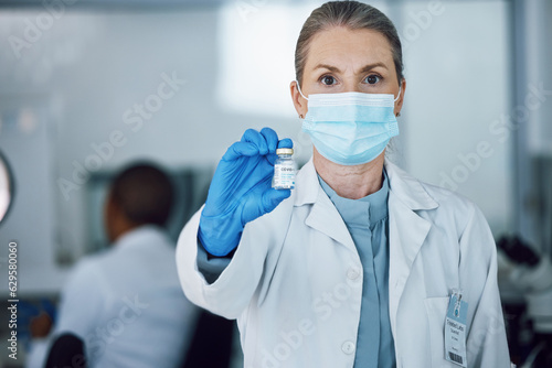 Portrait of woman doctor with face mask and vaccine bottle in hand at hospital laboratory for covid research. Healthcare  medicine and medical professional with sample for corona vaccination in lab.