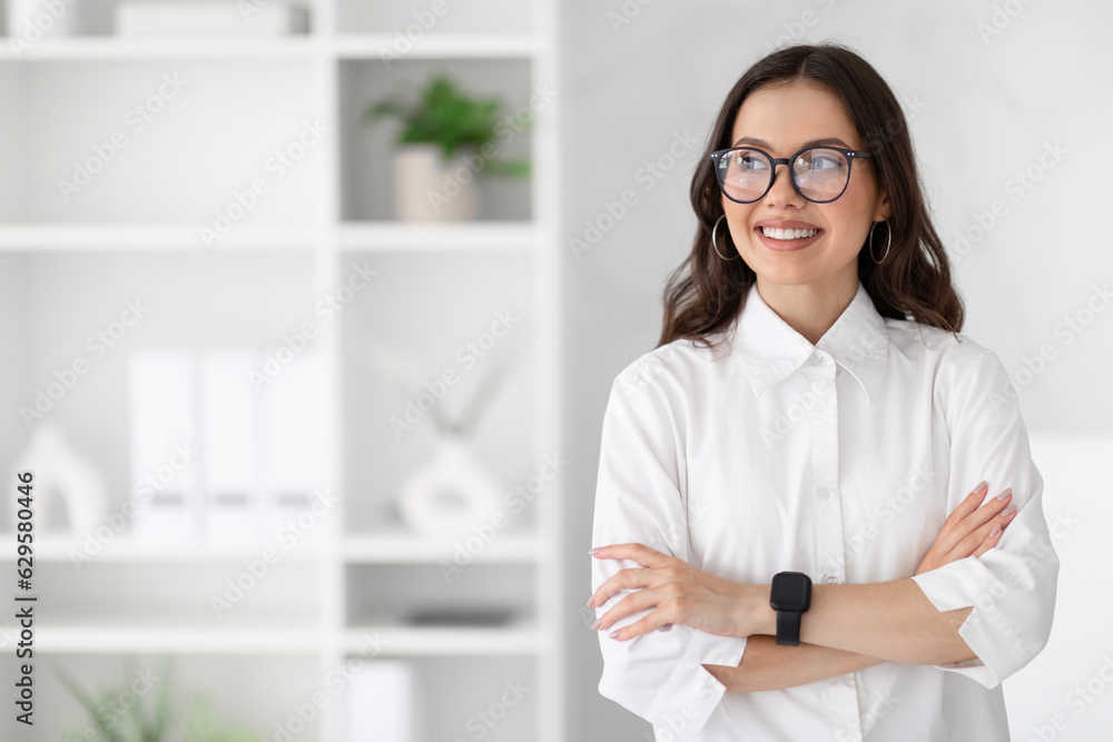 Cheerful young caucasian business woman in white shirt and glasses enjoys professional occupation, looking at copy space