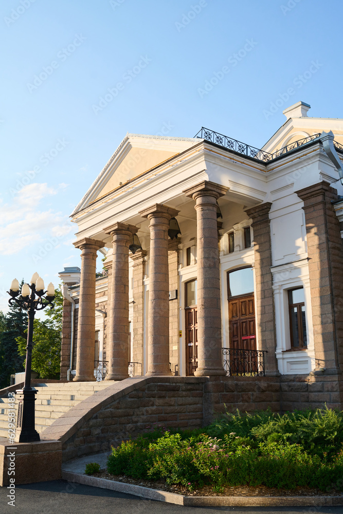 Facade of architectural monument of classic style with columns, street lamps and staircase standing in urban environment