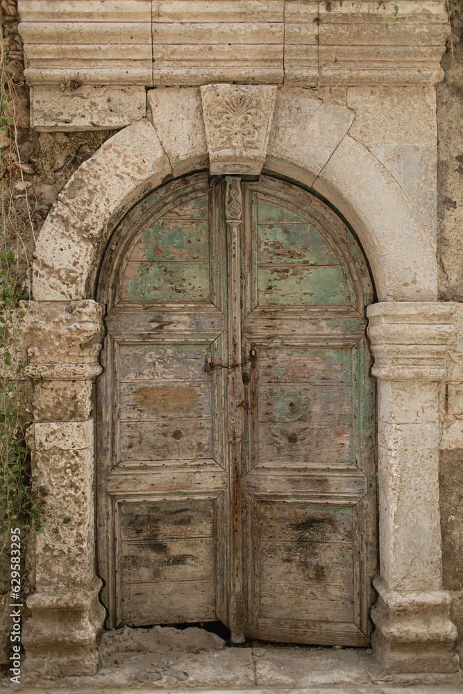 Old ancient colourful textured door in a stone wall in Greece, Crete. Vintage doorway. Traditional European, Greek architecture. Summer travel