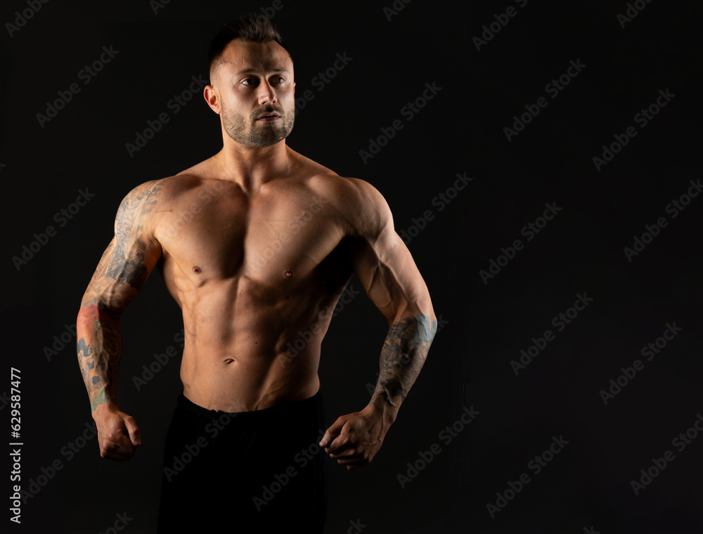 Strong muscular man on a black background, studio photo. Bodybuilding, torso muscles.