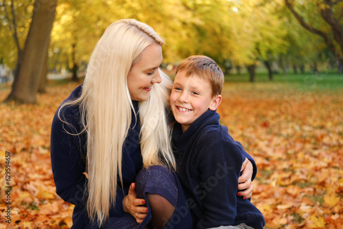 Mother and son in autumn park. Mother hugging son  son smiling